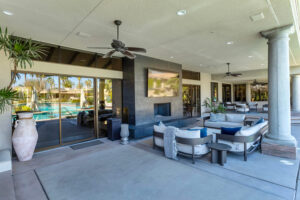 A modern living room with light wood floors, a cozy fireplace, and sleek floor-standing speakers near a frame-style TV.