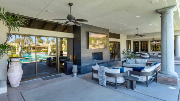 A modern living room with light wood floors, a cozy fireplace, and sleek floor-standing speakers near a frame-style TV.