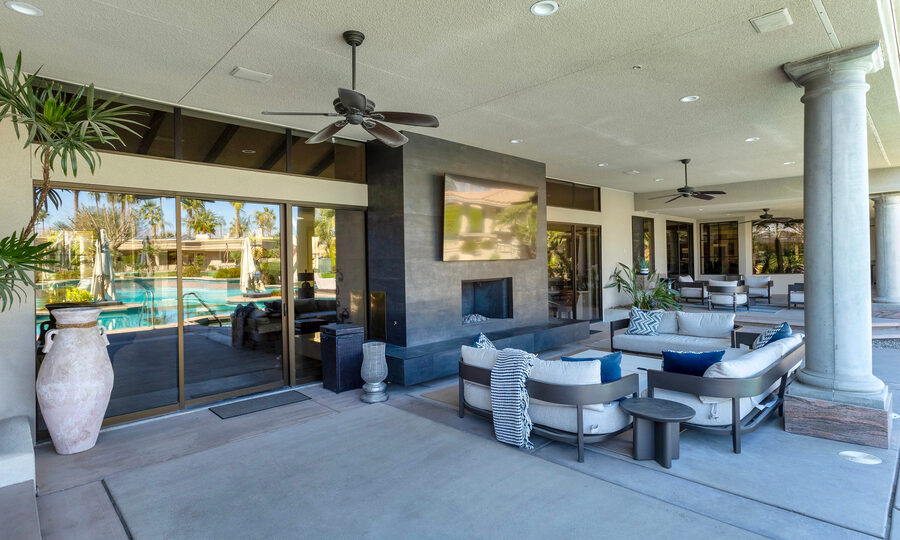 A modern living room with light wood floors, a cozy fireplace, and sleek floor-standing speakers near a frame-style TV.