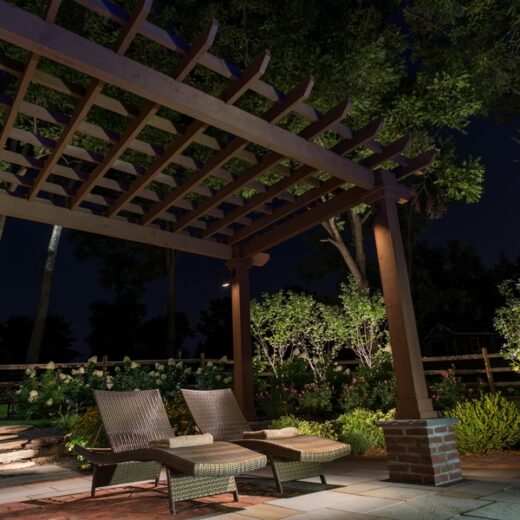 Outdoor patio illuminated by landscape lighting at night.
