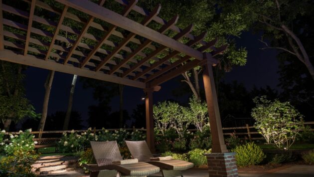 Outdoor patio illuminated by landscape lighting at night.