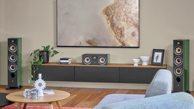 Green Focal Aria Evo X tower speakers and center channel flank a wall-mounted TV in a modern living room.