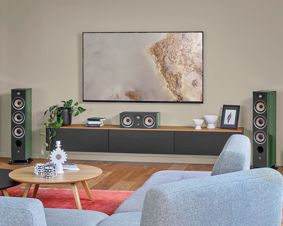 Green Focal Aria Evo X tower speakers and center channel flank a wall-mounted TV in a modern living room.